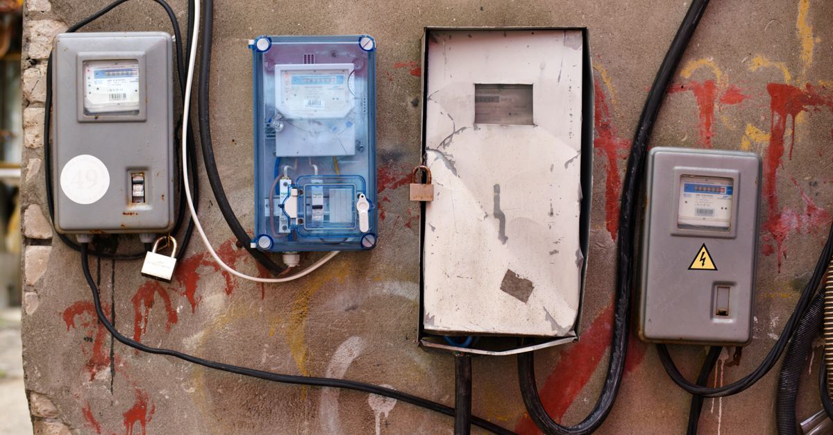 Electrical meters attached to a graffiti-covered wall showcasing utility infrastructure.
